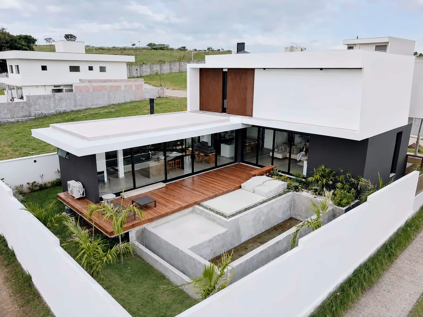 Vista aérea de casa com deck, piscina e portas de correr de piso a teto em alumínio preto