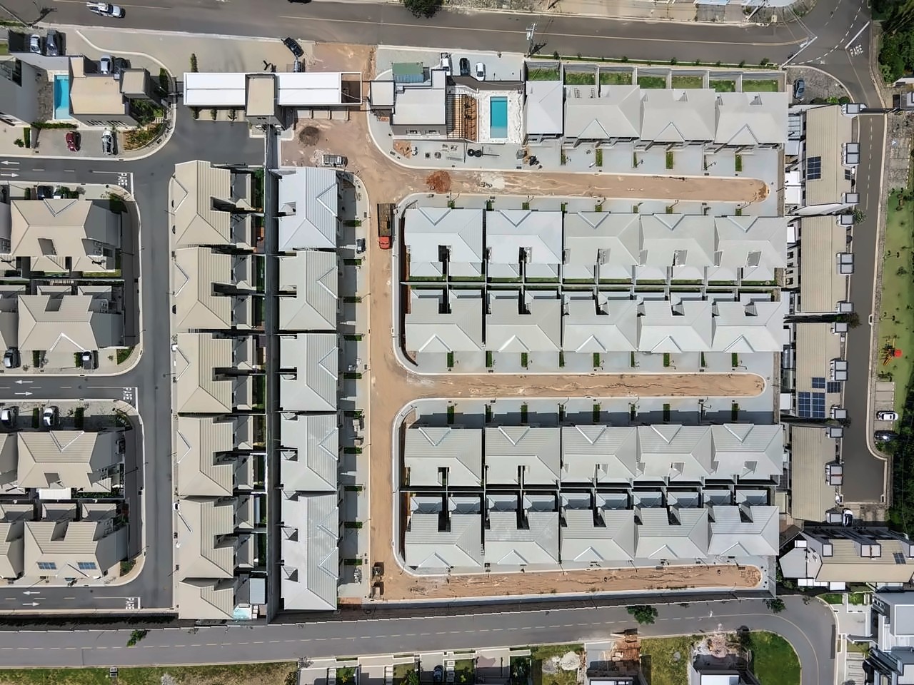 Vista de cima de vila residencial com quatro quadras de sobrados geminados, em fase final de obra